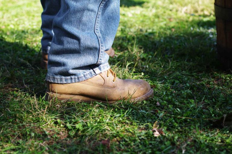 Boot of a Man Wearing Blue Jeans in the Grass
