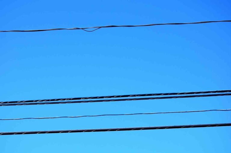 Black telephone and electric wires against a blue sky stock photo